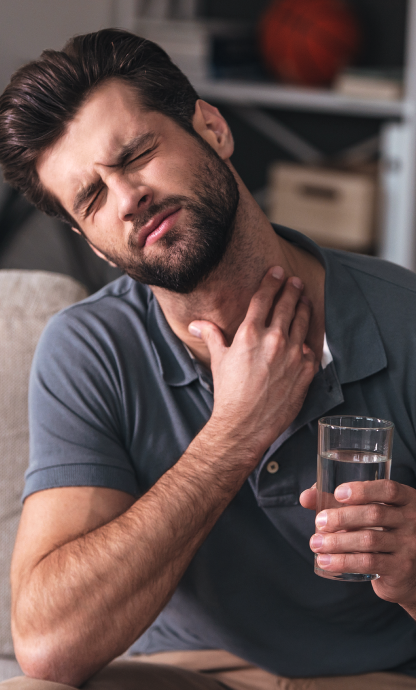 Uomo dolorante che si tocca il collo con la mano destra e sorregge un bicchiere d'acqua con la sinistra